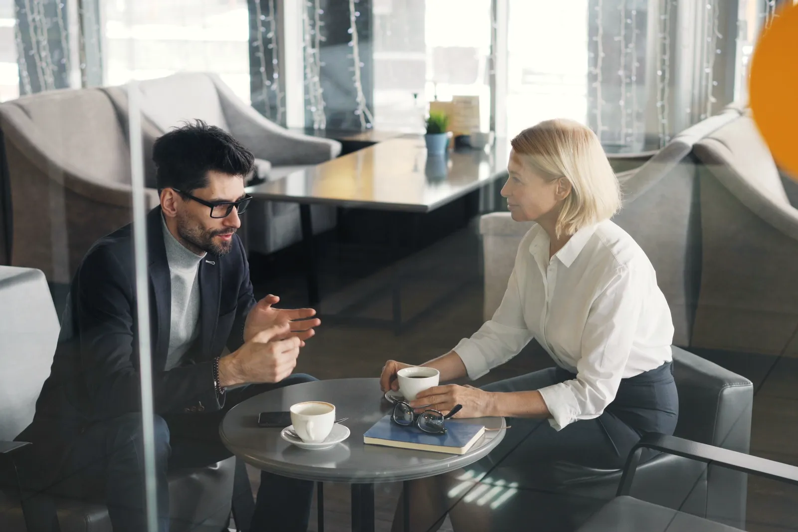 Ein Kundenbetreuer und eine Kundin sprechen bei einer Tasse Kaffee über ihre Pläne