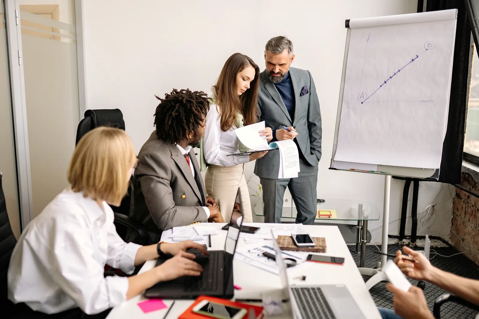 Ein Vertriebsteam bespricht in einem hellen Büro am Flipchart, wer welche Kunden übernimmt